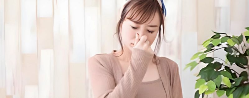 悪臭を嗅いで嫌がる女性。鼻をつまんで顔をしかめる女性