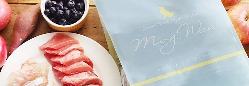 モグワンドッグフードの原材料。鶏肉や野菜、果物が木のテーブルに置かれている